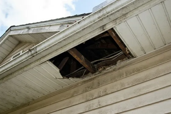 A house eave with a section of soffit missing, exposing the rafter cavity